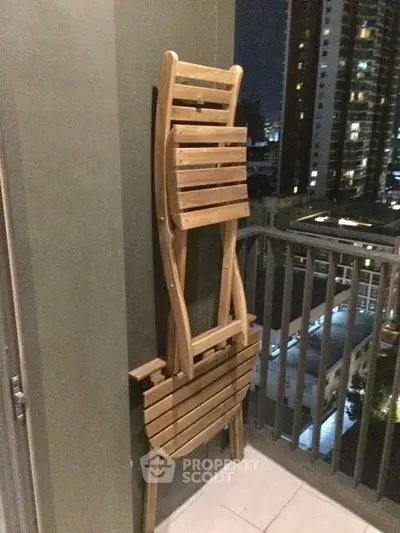 Stylish balcony with city view and wooden folding chairs, perfect for urban living.