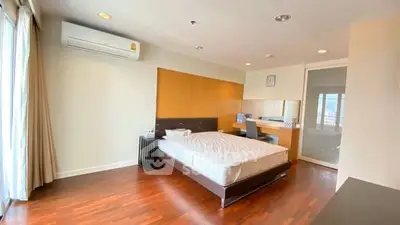 Spacious modern bedroom with hardwood floors and large window in luxury apartment.