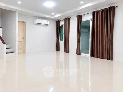 Spacious empty living room with glossy tiled floors, air conditioning, and elegant brown curtains.