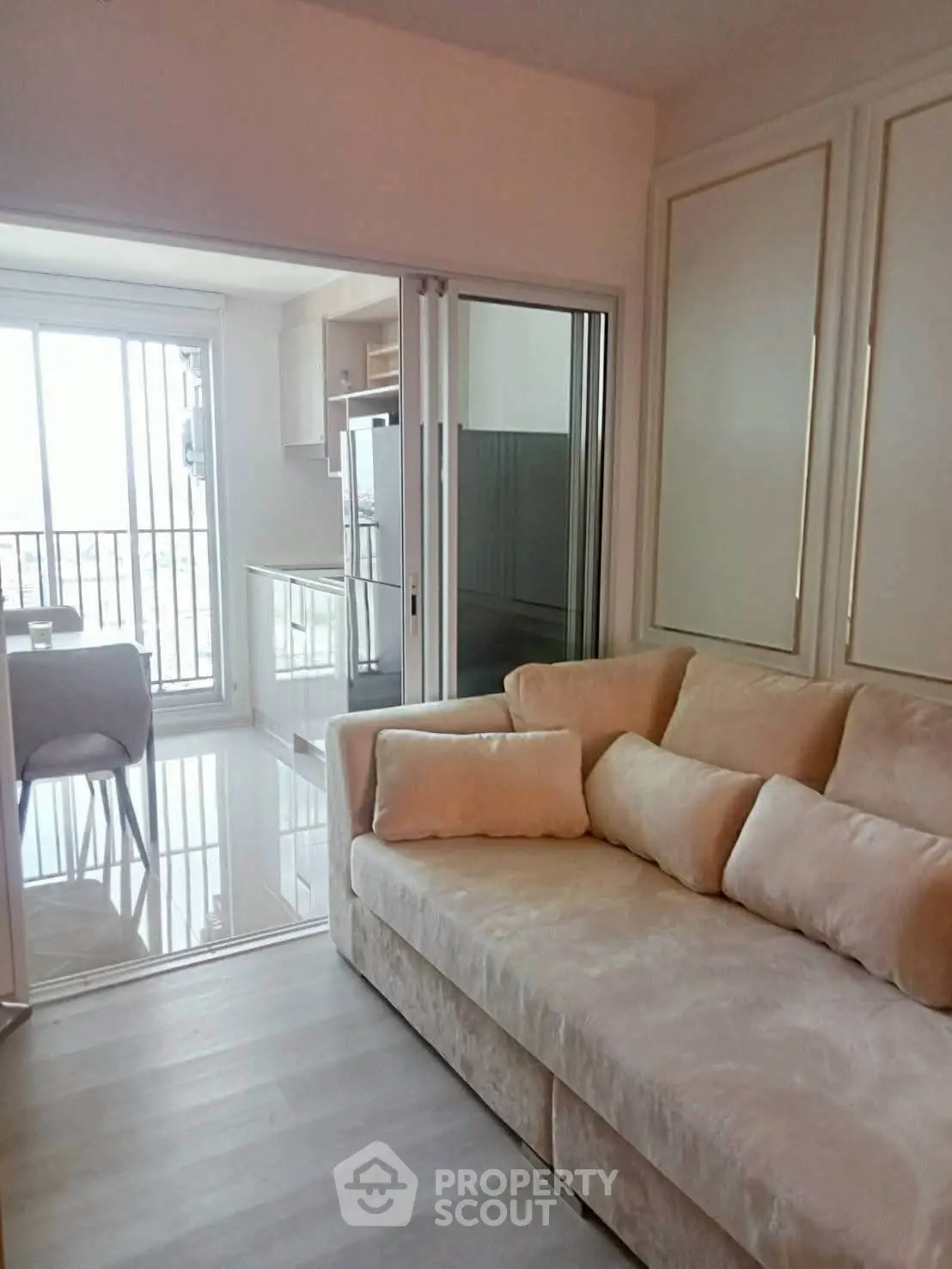 Modern living room with sliding glass doors leading to a bright balcony and kitchen area.