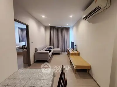 Modern living room with cozy sofa and TV, open layout to bedroom, air-conditioned comfort.