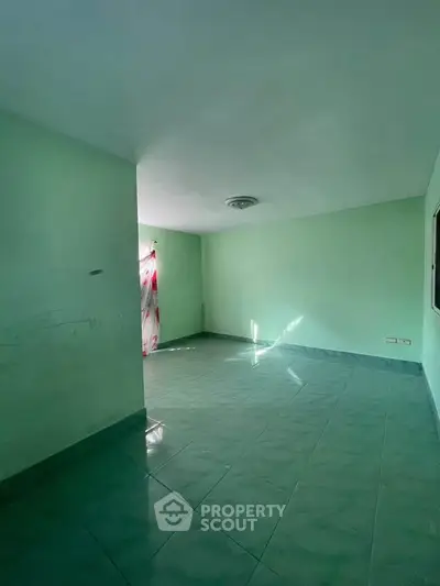 Spacious empty room with green walls and tiled floor, ideal for customization.