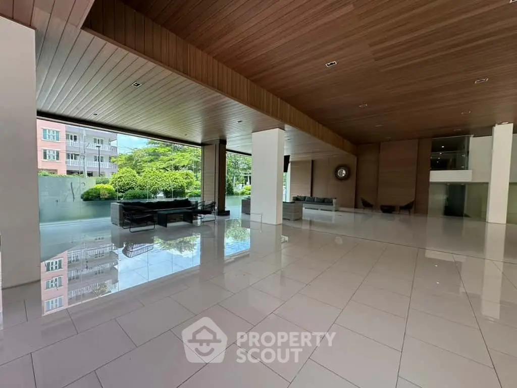 Spacious modern building entrance with sleek design and lush greenery view.