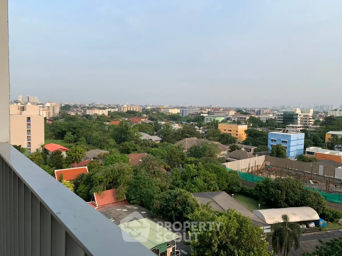 Stunning cityscape view from a high-rise balcony overlooking lush greenery and urban skyline.