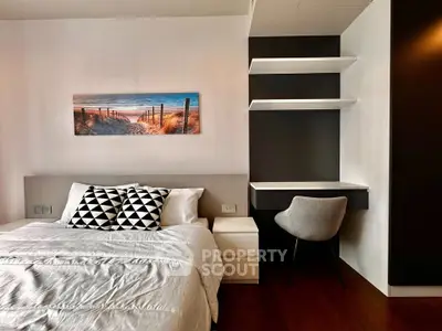 Modern bedroom with stylish decor and cozy workspace, featuring elegant bedding and wall art.
