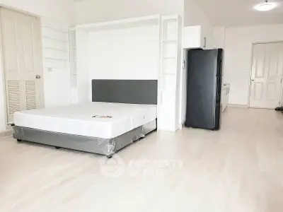 Spacious studio apartment with modern furnishings and sleek kitchen appliances.