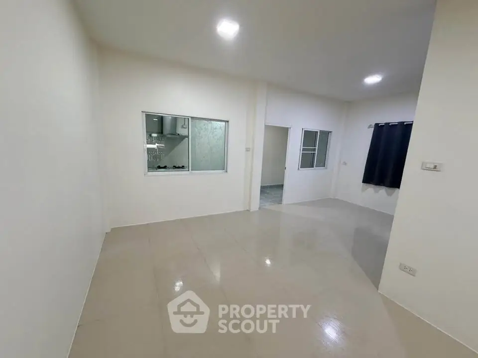 Spacious unfurnished room with tiled flooring and large window, ideal for customization.