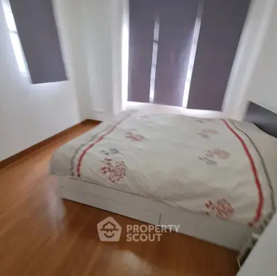Cozy bedroom with wooden flooring and modern decor, featuring a comfortable bed and ample natural light.