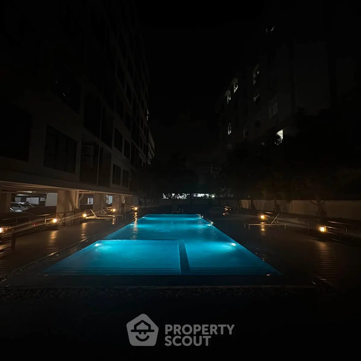 Luxurious night view of illuminated swimming pool in modern residential complex.