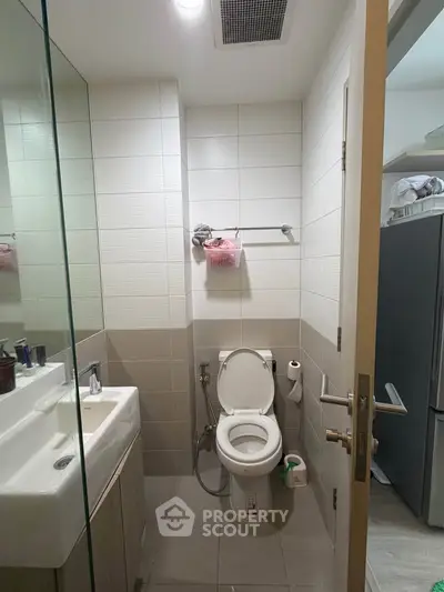 Modern bathroom with sleek fixtures and neutral tiles, featuring a glass shower and contemporary design.