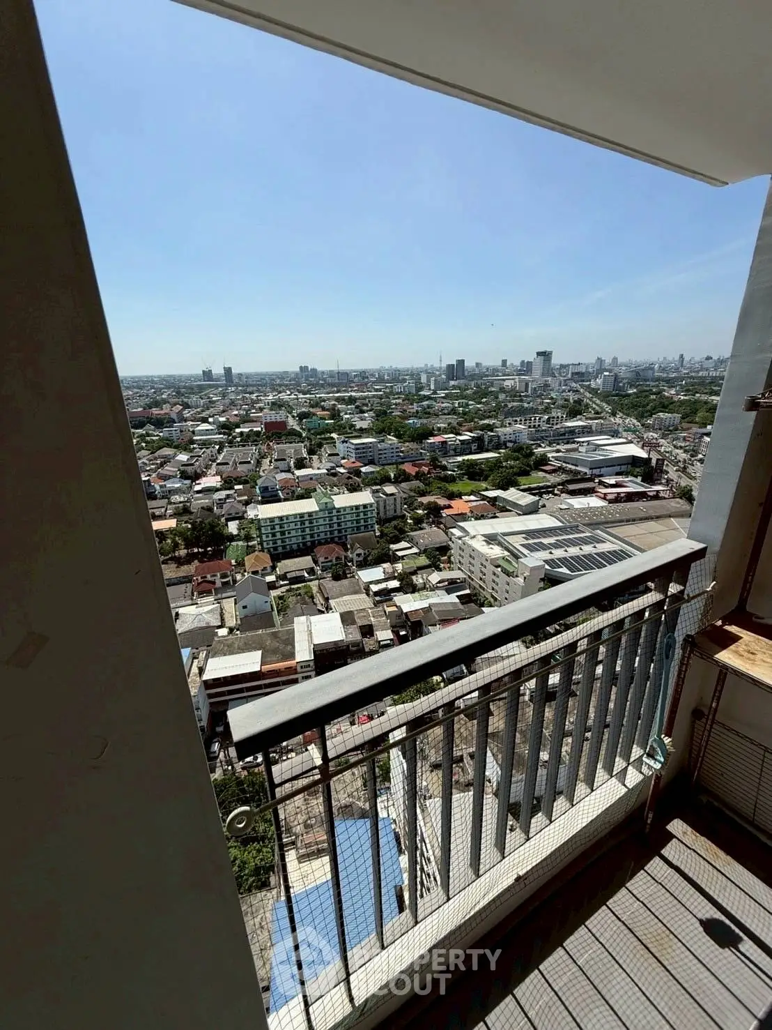Stunning high-rise balcony view overlooking cityscape with clear skies.