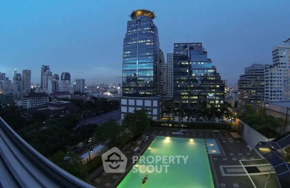 Stunning cityscape view with illuminated pool and modern high-rise buildings at dusk.