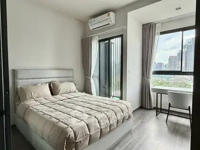 Modern bedroom with city view, featuring a cozy bed and stylish decor, perfect for urban living.