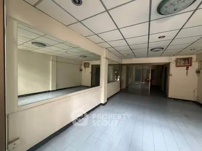 Spacious interior with tiled flooring and mirrored wall, ideal for customization.