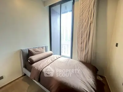 Cozy bedroom with single bed and floor-to-ceiling window offering natural light and modern design.
