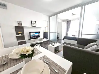 Modern open-plan living room with stylish decor and cozy bedroom view.