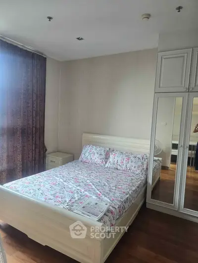 Cozy bedroom with floral bedding and mirrored wardrobe in modern apartment