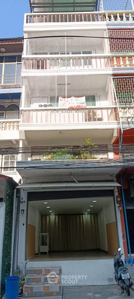 Spacious multi-story building with open garage and balcony, ideal for urban living or business use.