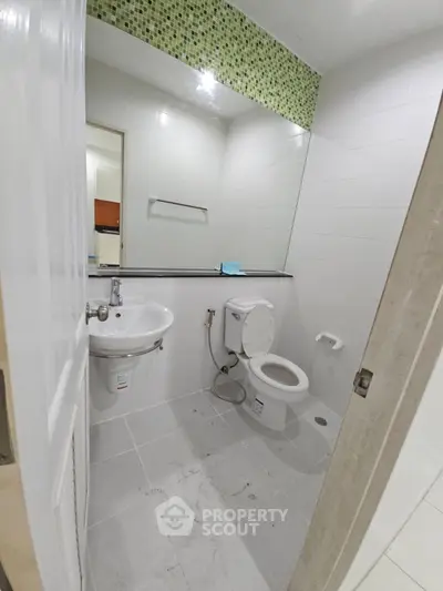 Modern bathroom with sleek fixtures and stylish green mosaic tile accent.