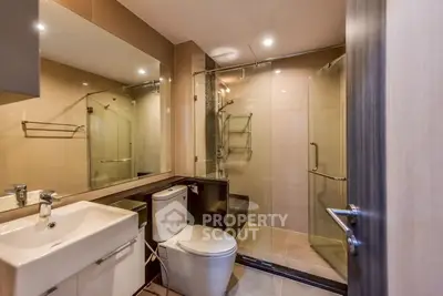 Modern bathroom with glass shower and sleek fixtures in contemporary apartment.