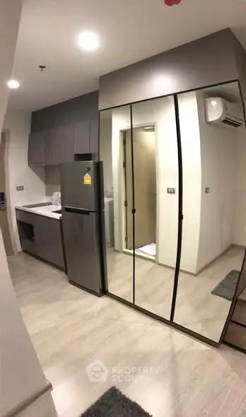 Modern kitchen with sleek cabinetry and mirrored closet doors in a stylish apartment.