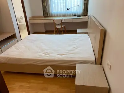 Cozy bedroom with wooden furniture and natural light, ideal for relaxation.