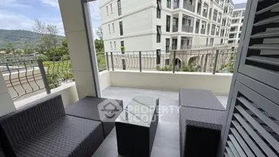 Spacious balcony with modern outdoor seating and scenic view in luxury apartment complex.