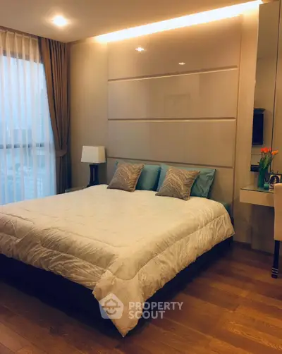Elegant bedroom with modern decor and large window offering natural light.