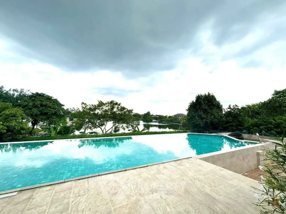 Luxurious infinity pool with serene lake view and lush greenery, perfect for relaxation and leisure.