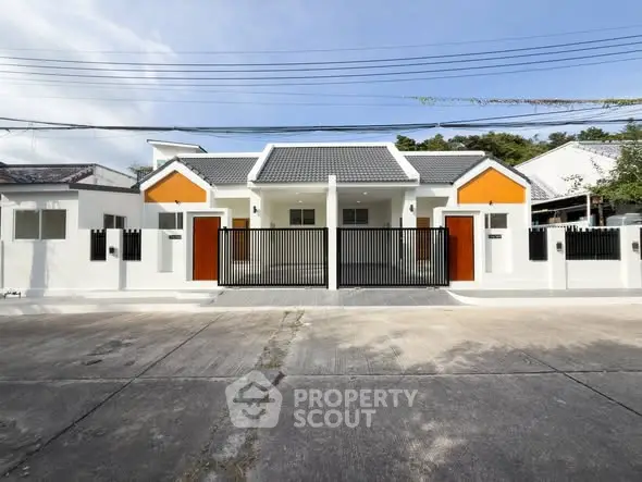 Modern single-story house with gated entrance and vibrant orange accents.