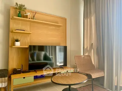 Cozy living room with modern TV stand, stylish chair, and natural light through curtains.