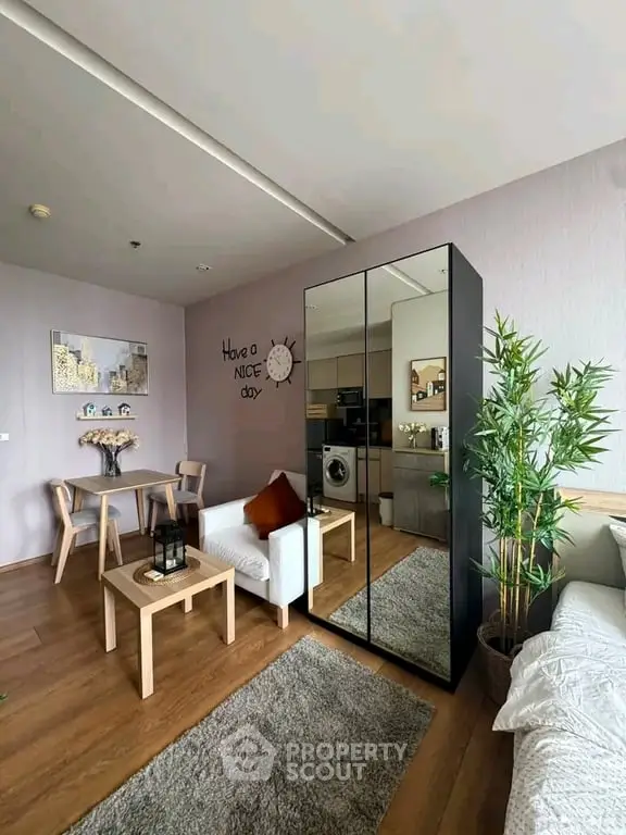 Modern living room with stylish decor and compact kitchen area, featuring a cozy seating arrangement and mirrored wardrobe.