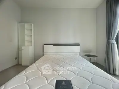 Spacious bedroom with modern furnishings and large window for natural light.