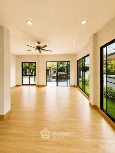 Spacious living room with large windows and garden view, perfect for natural light lovers.