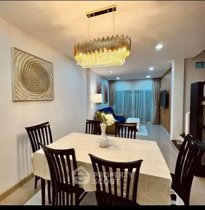 Elegant dining area with modern chandelier and cozy living room in open layout apartment.