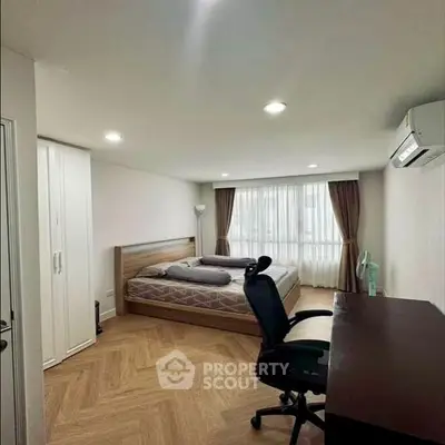 Spacious bedroom with modern furnishings and large window for natural light.