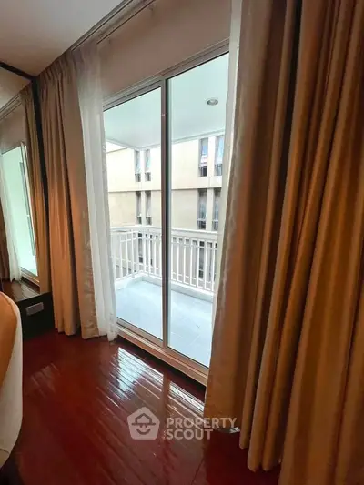 Elegant bedroom with polished wooden floors and balcony access through sliding glass doors.