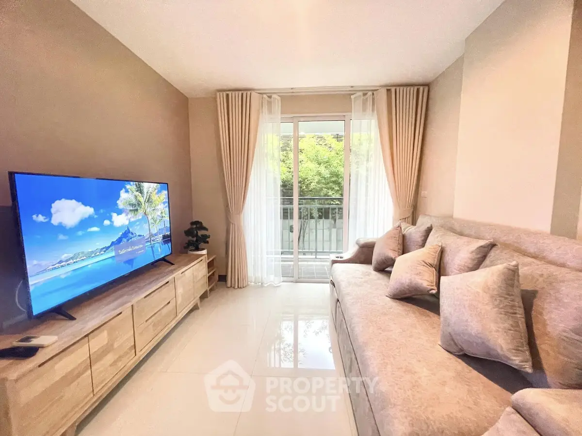 Bright living room with large TV and cozy sofa, featuring a balcony view.