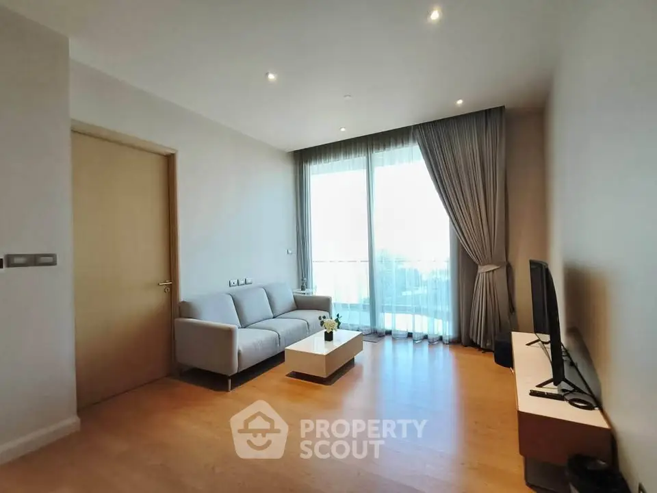 Modern living room with sleek furniture and large window offering natural light.