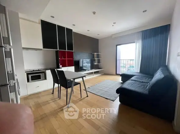 Modern living room with open kitchen, sleek furniture, and natural light.