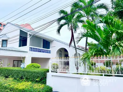 Charming white house with lush garden and balcony, perfect for serene living.