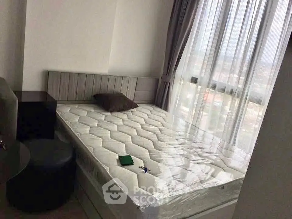 Cozy bedroom with large window offering natural light and city view, featuring a comfortable bed and modern decor.