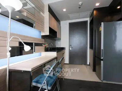 Modern kitchen with sleek design, featuring a dining area and stainless steel appliances.