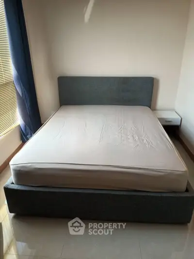 Spacious bedroom with modern bed and natural light from large window.