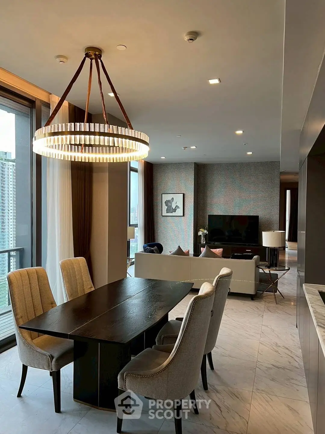Luxurious open-plan living and dining area with elegant chandelier and city view.