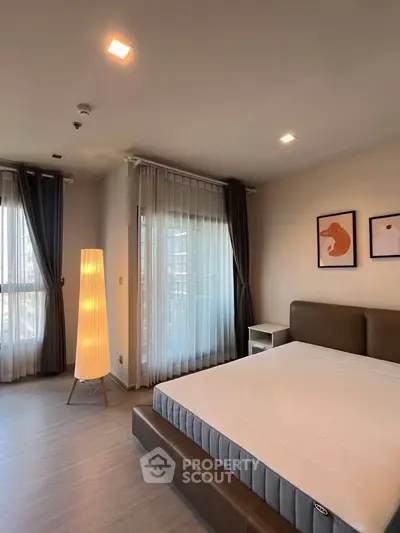 Spacious bedroom with modern decor and large windows offering natural light.