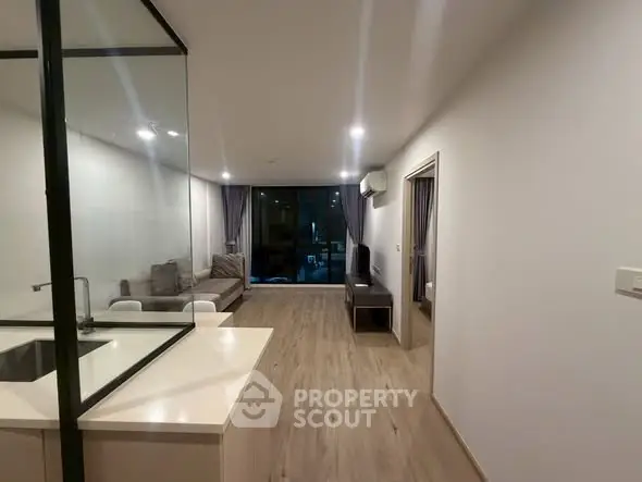 Modern living room with open layout and sleek design, featuring a cozy sofa and large windows.