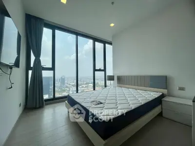 Spacious bedroom with large windows offering stunning city views, modern furnishings, and ample natural light.