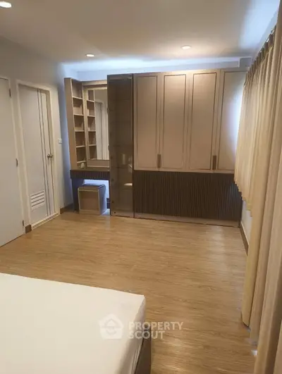 Spacious bedroom with built-in wardrobe and wooden flooring in modern apartment.