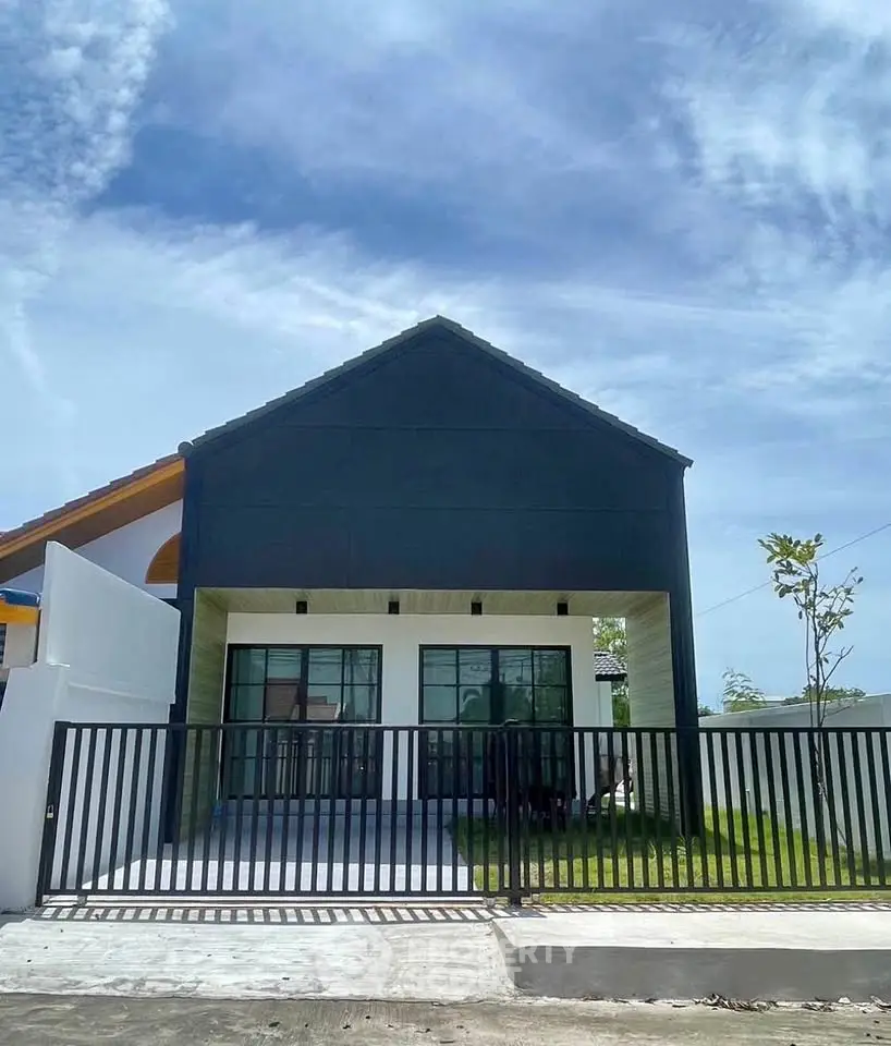 Modern single-story house with sleek black facade and gated entrance.